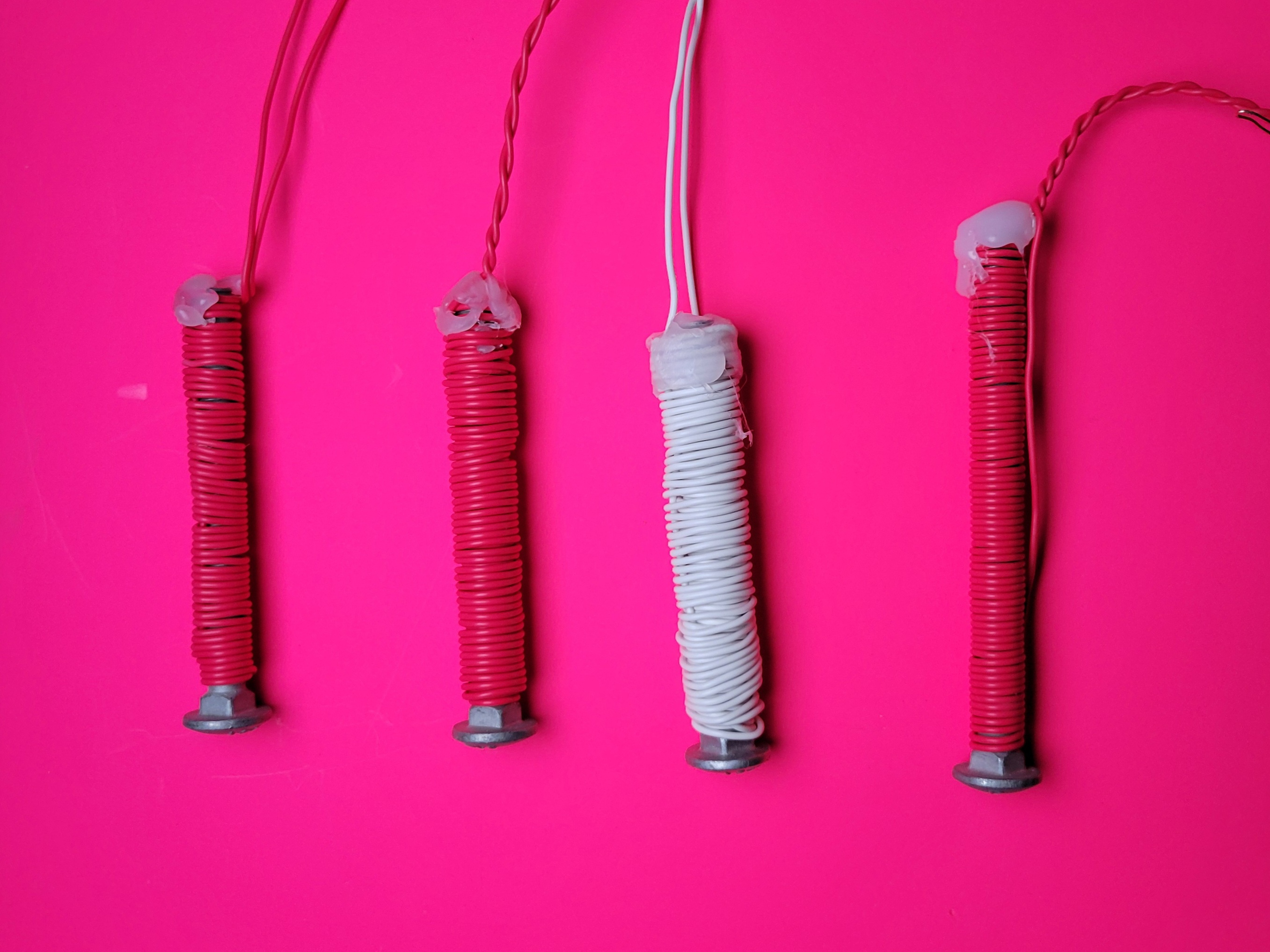 Several coiled bolt electromagnets on a pink background